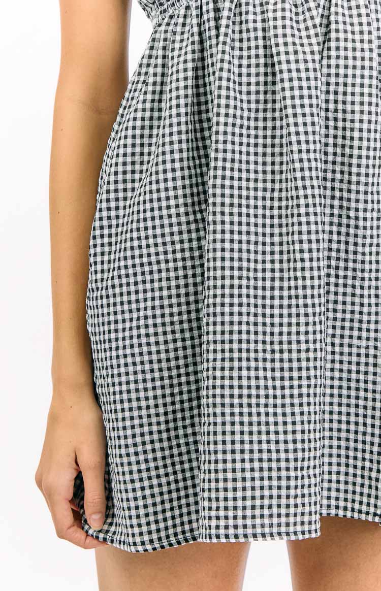 Close-up of the gathered black gingham fabric of the mini dress skirt and its hemline