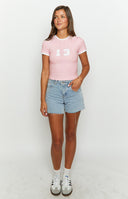 Girl in white dress and girl in pink baby tee smiling facing each other.