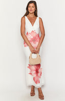 Girl wearing floral print maxi dress and white heels holding a cocktail glass.