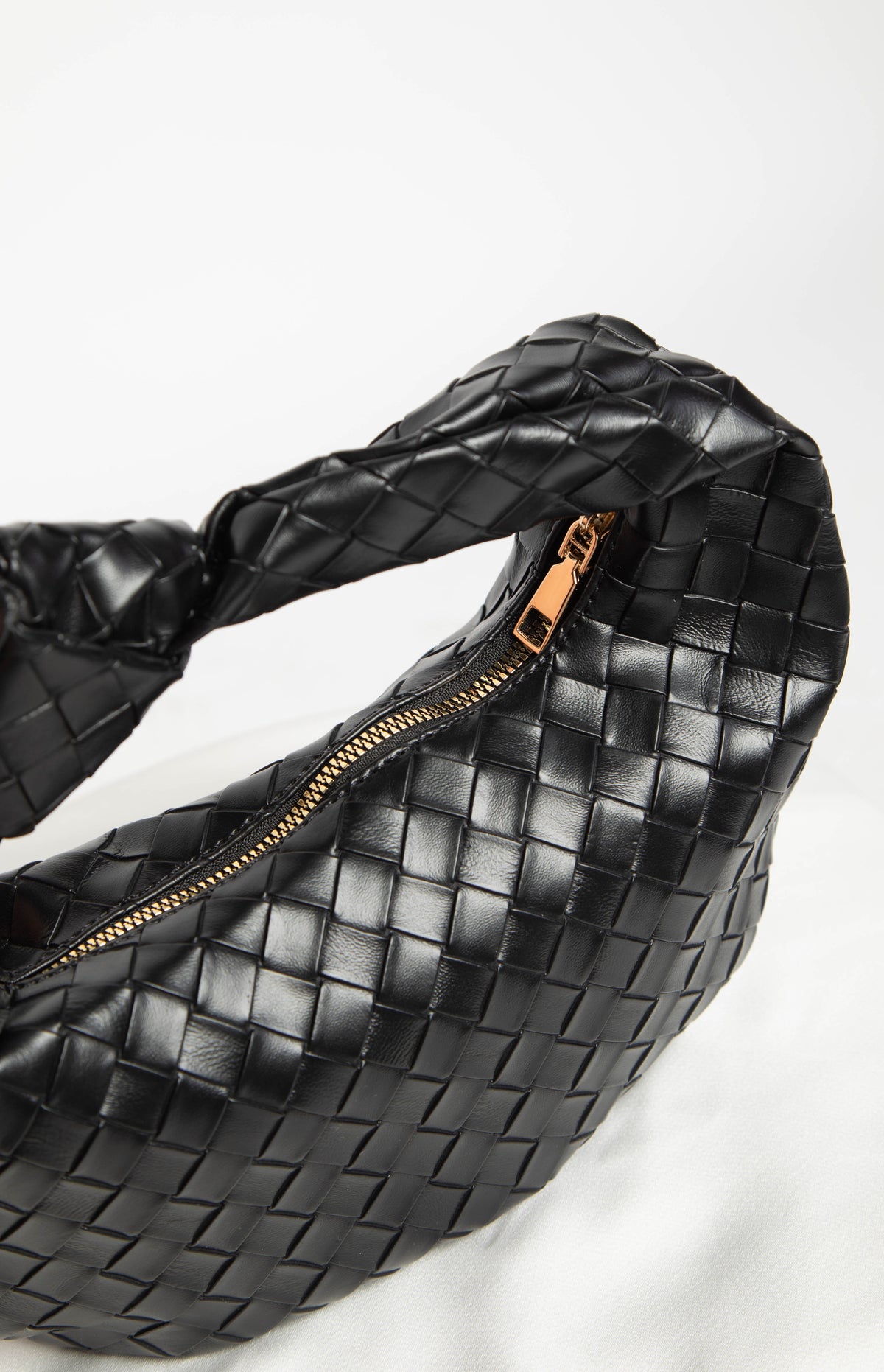 Close-up of the black woven PU shoulder bag showing the gold-toned zipper and textured material