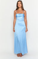 blonde model wearing a strap-back blue maxi dress with ruched lower back, gold bracelet and white hand bag