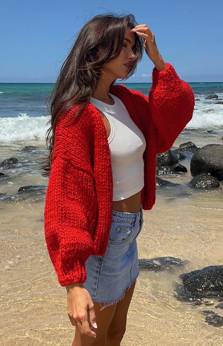 Side view of the red chunky knit cardigan, highlighting its thick texture and oversized balloon sleeves