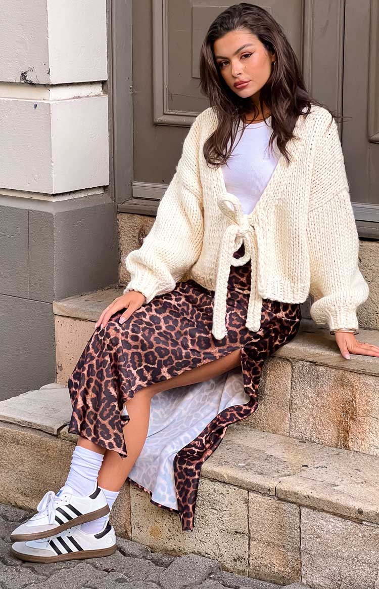 Cream chunky knit cardigan with a front tie closure, long sleeves, and a relaxed cropped fit