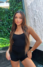 Black ribbed playsuit with a scoop neckline, thin spaghetti straps, and fitted shorts