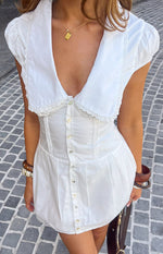 White collared mini dress with deep V-neck, lace trim, puffed sleeves, button front, and corset bodice