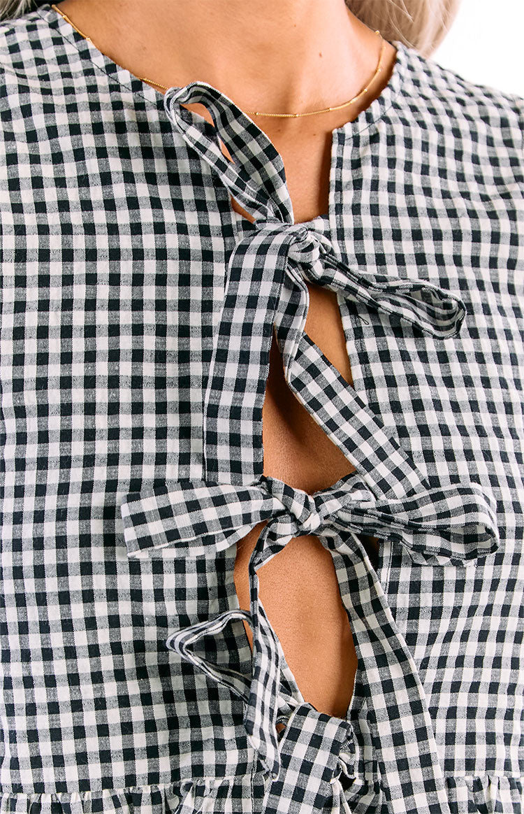 Close-up of the black and white gingham top's split V-neckline with two tied bows creating a keyhole detail