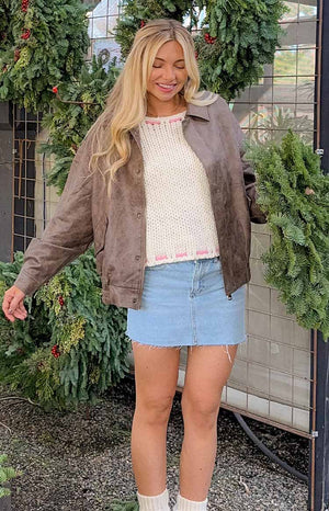 Cream chunky knit sweater with pink trim at the round neckline and hem