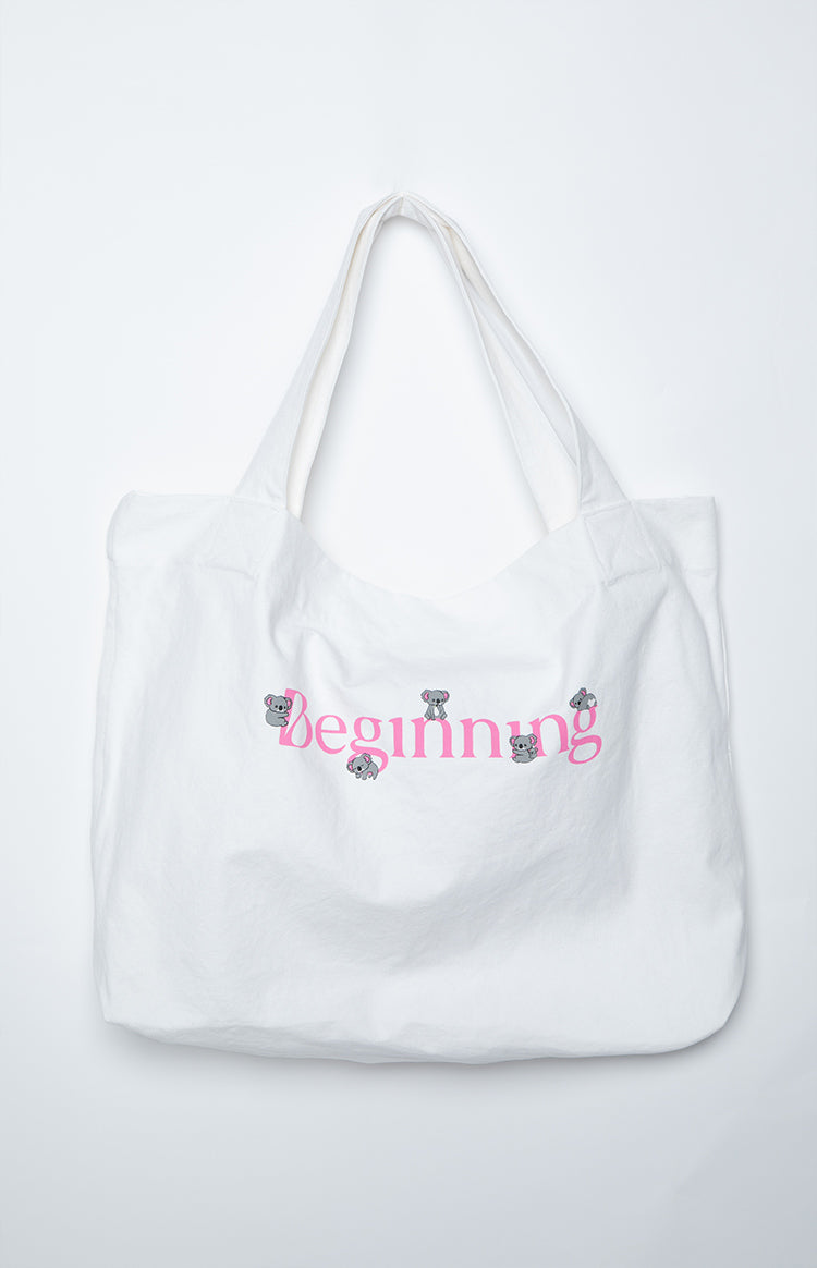 White canvas tote bag with pink 'Beginning' text and small grey koala illustrations