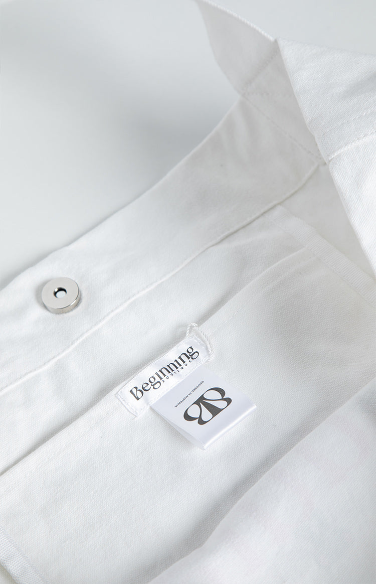 Interior view showing the magnetic snap closure and woven brand label of the white tote bag