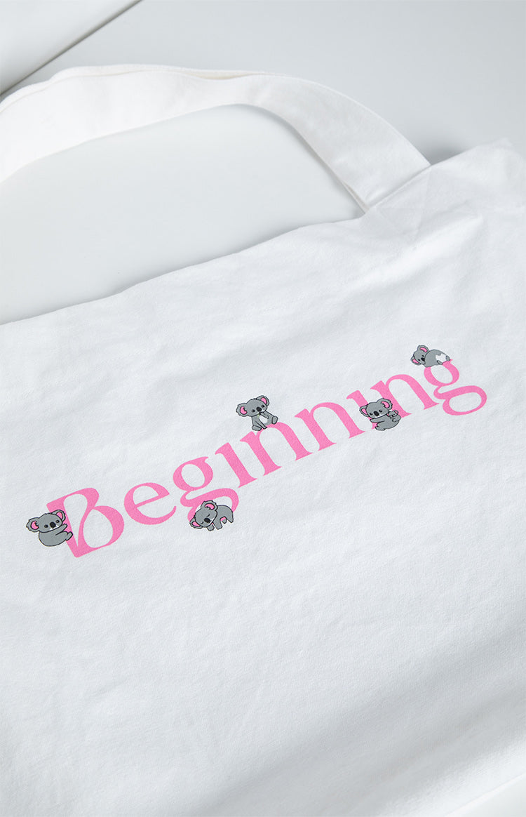 Close-up of the pink 'Beginning' text with small grey koala graphics on a white tote bag