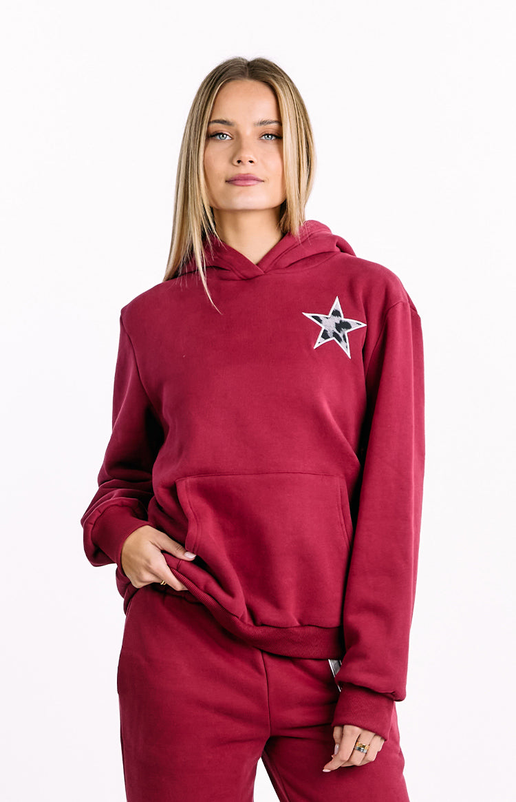 Front view of a burgundy oversized hoodie with a grey leopard print star on the left chest and a large kangaroo pocket