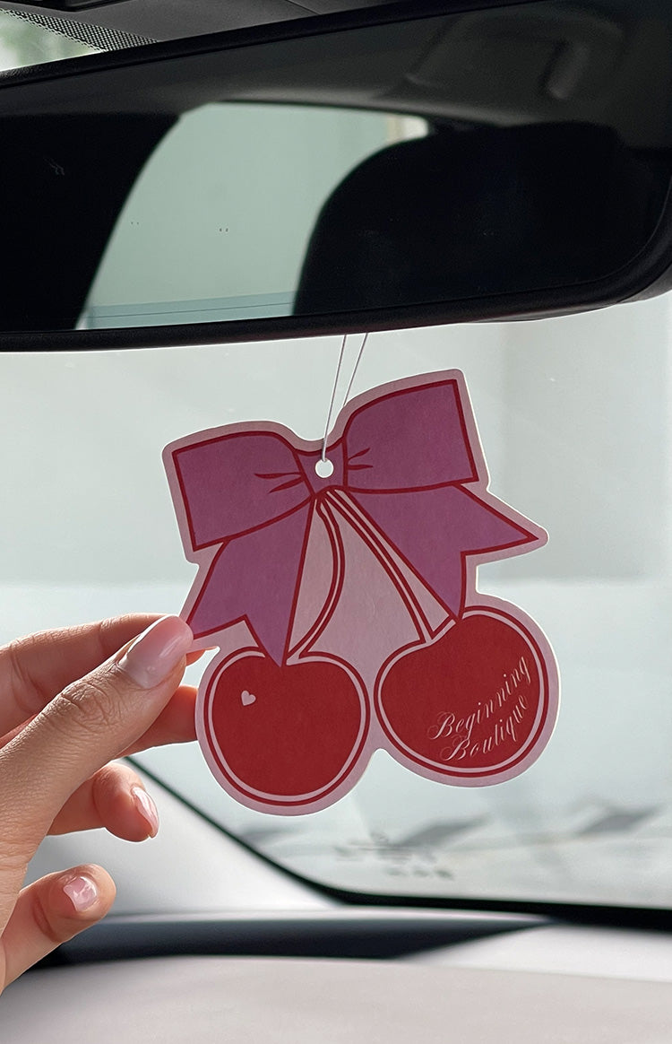Pink bow and red cherry air freshener with Beginning Boutique text on the right cherry