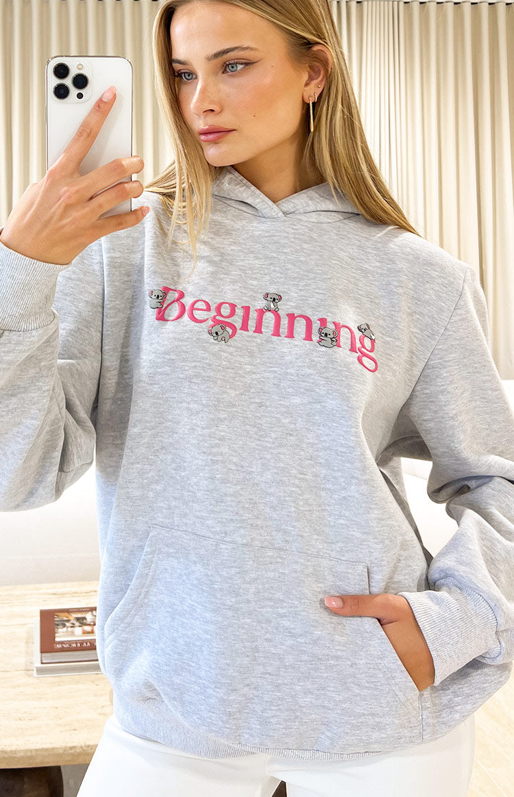 Close-up of the grey marl hoodie with pink 'Beginning' graphic featuring small koalas and a front kangaroo pocket