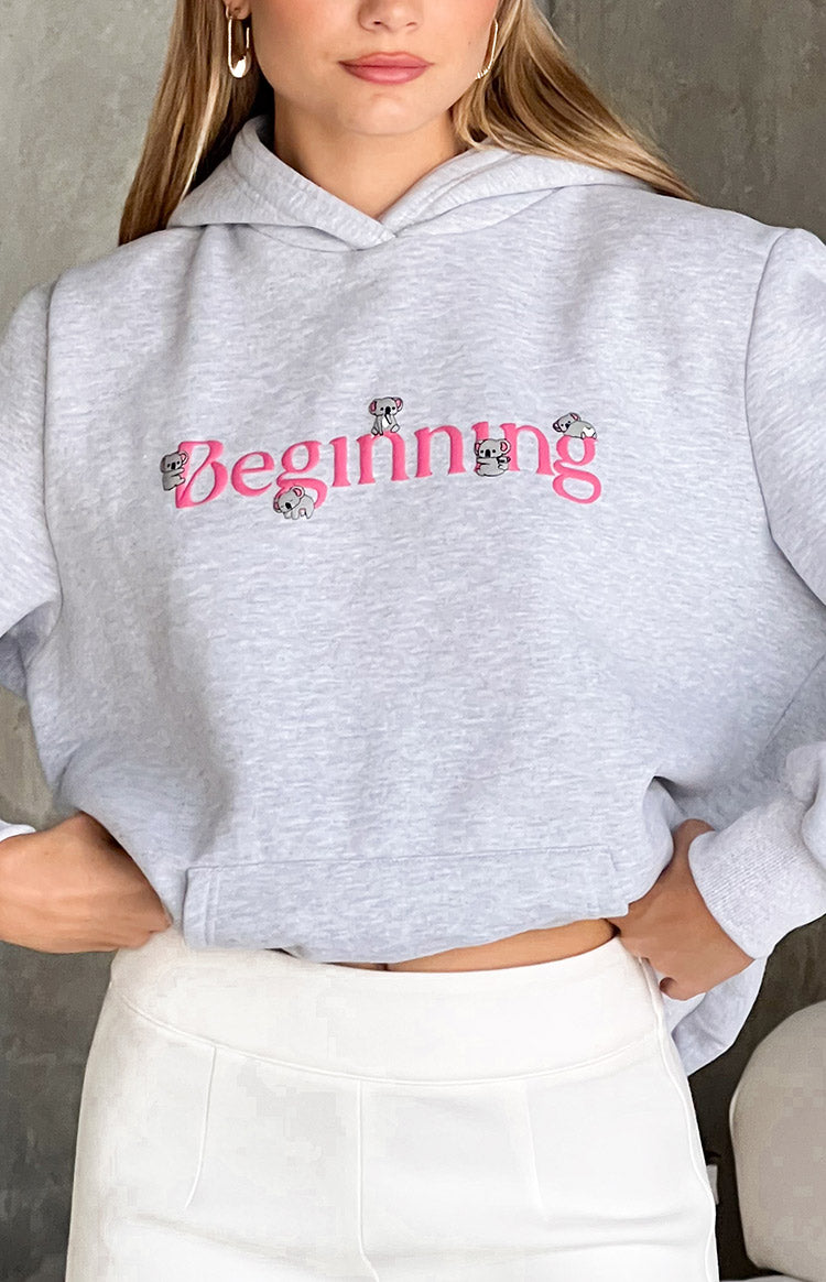 Close-up of the grey marl hoodie showing pink 'Beginning' embroidery with koala details