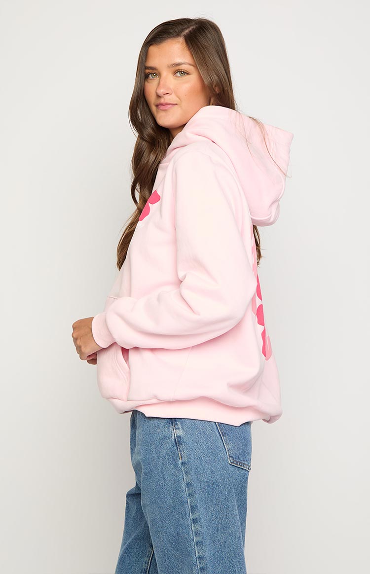 Side view of an oversized light pink hoodie with a hood, kangaroo pocket, and a darker pink graphic on the side