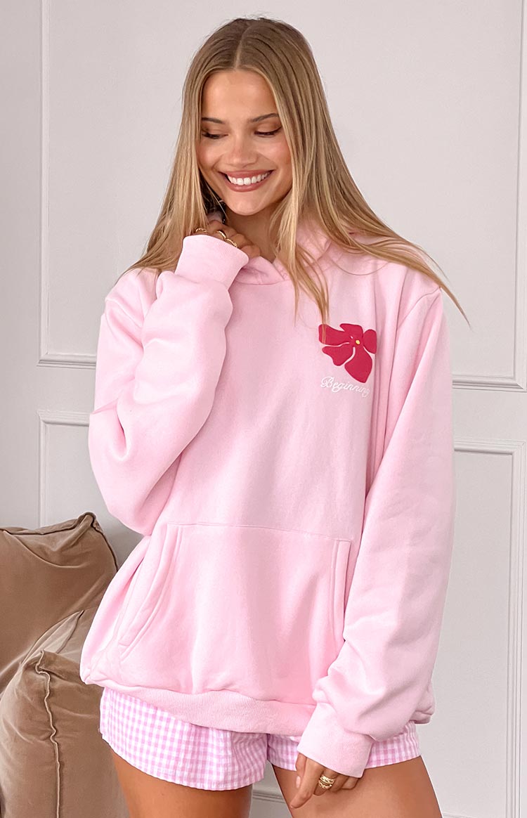 Pink oversized hoodie with front kangaroo pocket, ribbed cuffs, and red hibiscus graphic