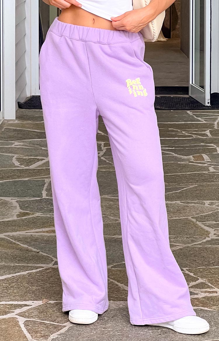 Close-up of the elasticated waistband and yellow logo on purple wide-leg track pants