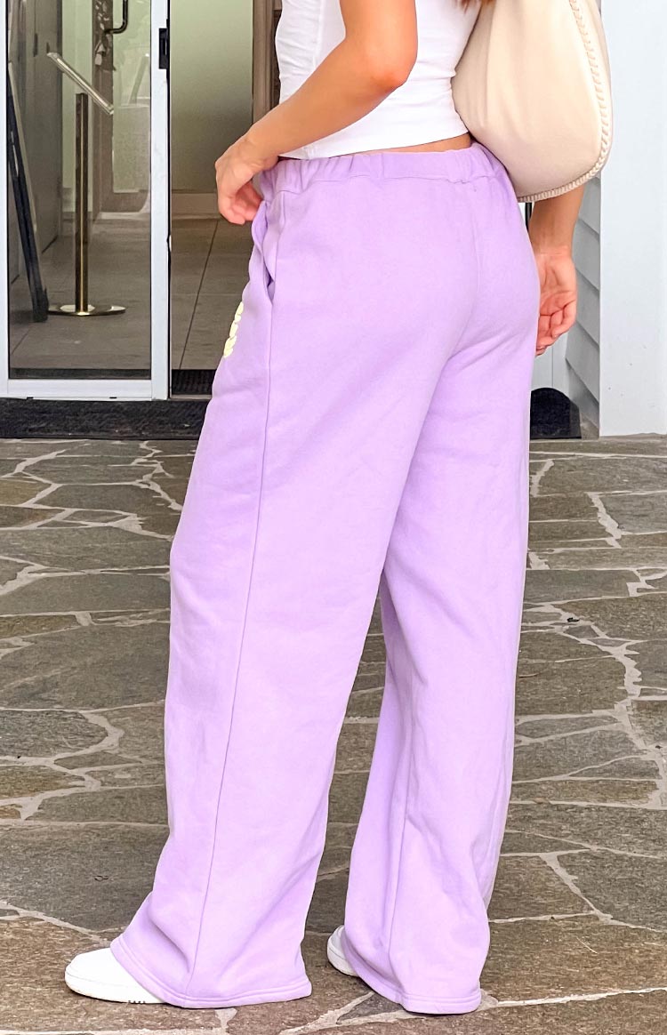 Side-rear view of purple wide-leg track pants with an elasticated waistband and side pockets