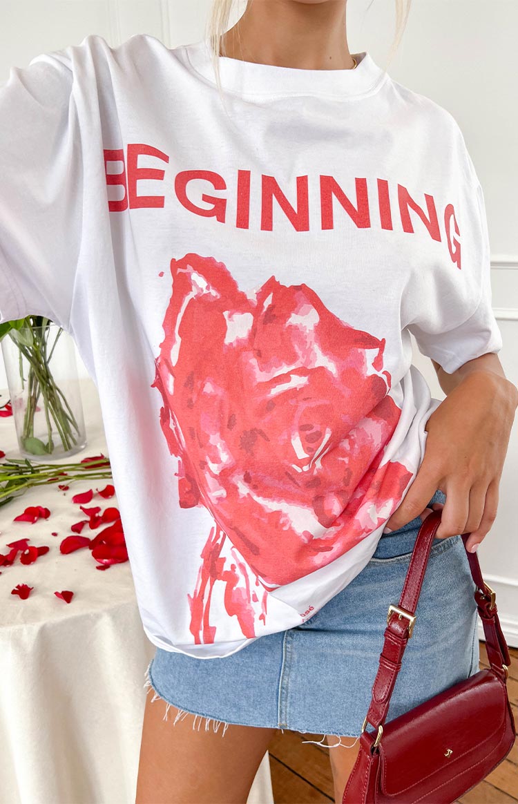 Close-up of the white oversized tee with red 'BEGINNING' text and large red rose graphic