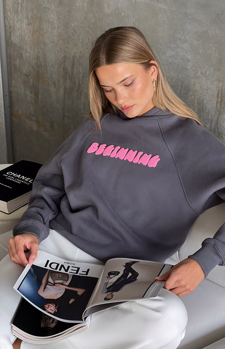 Close-up of the slate grey hoodie showing the pink bubble "BEGINNING" text and raglan sleeves
