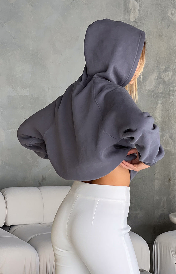 Rear view of a slate grey cropped hoodie with the hood up and a bubble hem