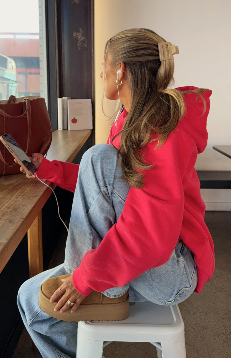 Side view of a watermelon red oversized hoodie with long sleeves and ribbed cuffs