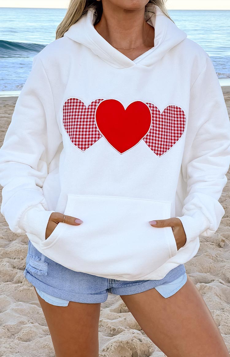 Close-up of the white hoodie showing the three heart appliques and front kangaroo pocket