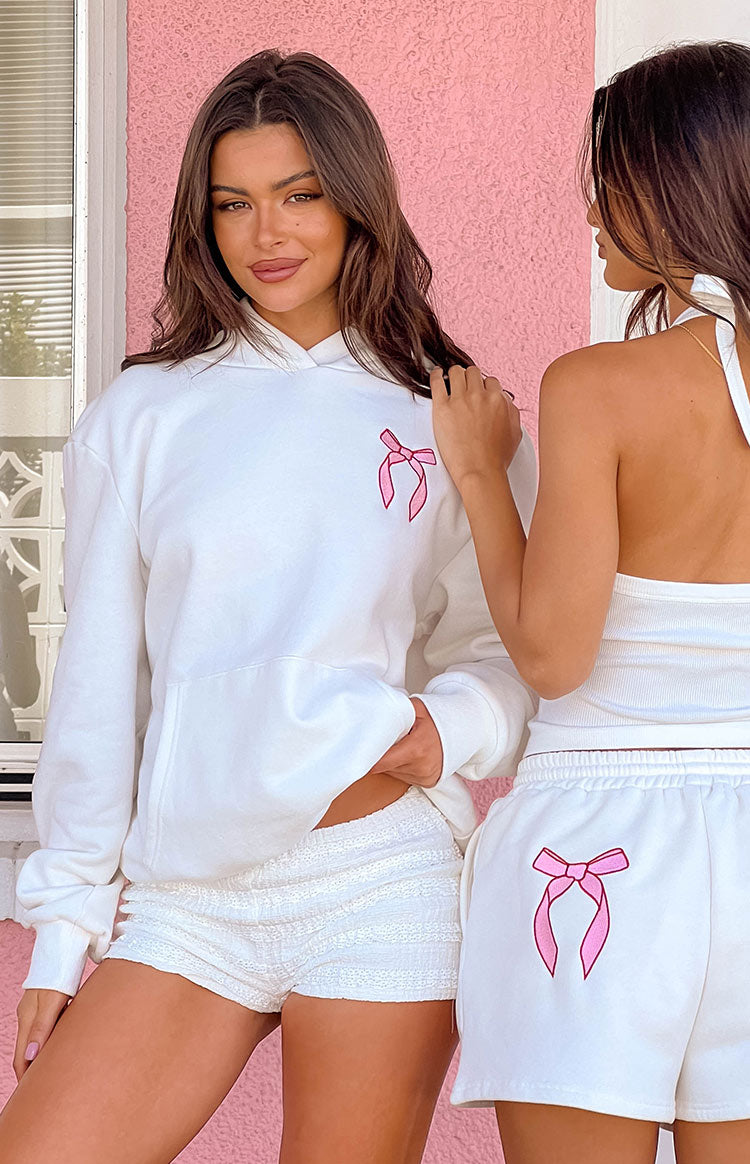 White oversized hoodie with a pink bow graphic on the chest and a front kangaroo pocket