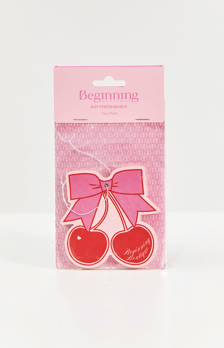 Two red cherry air fresheners with a pink bow and white string, in pink packaging with a BB logo pattern