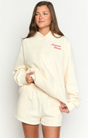 girl wearing a cream coloured hoodie with an emboidered red gingham cowboy boot and navy star on the back