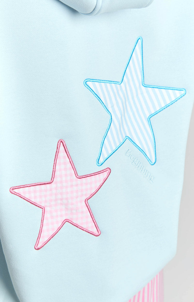 Close-up of light blue hoodie with pink gingham star and blue striped star appliques, and 'Beginning' embroidery