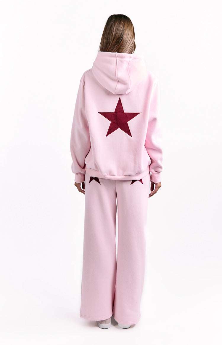 Rear view of a pink oversized hoodie with a large burgundy star and matching pink wide-leg pants with star details