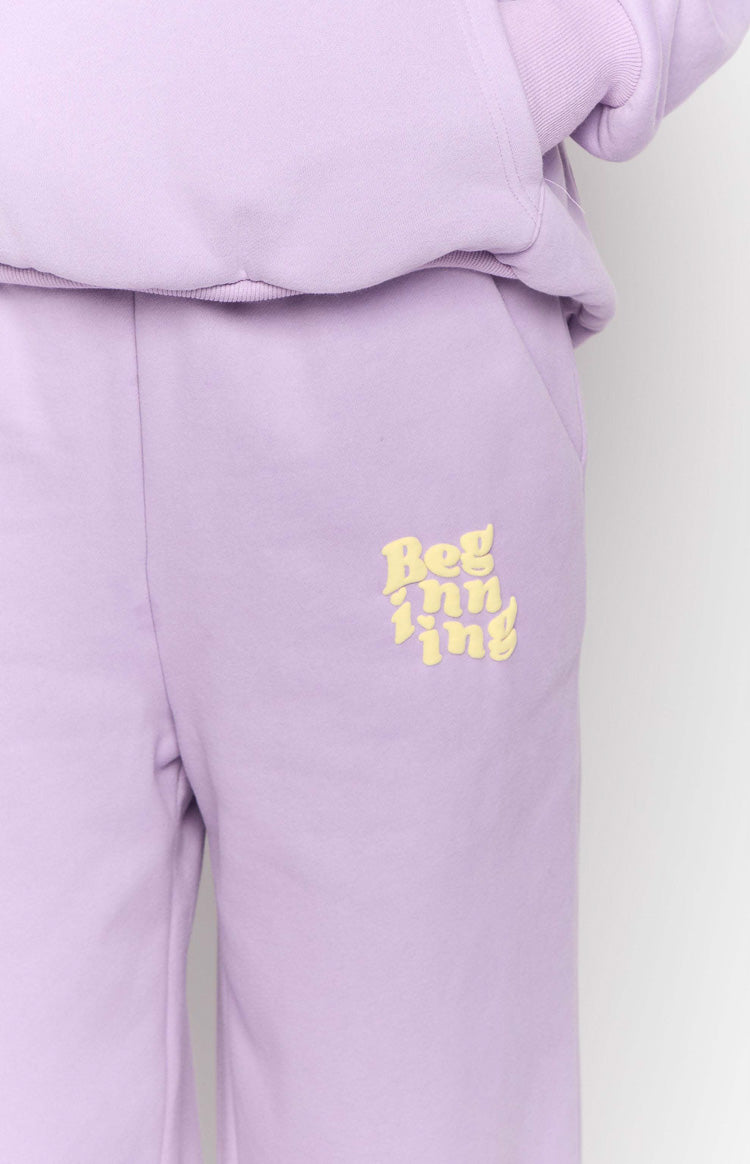 Close-up of the yellow embroidered text on the purple track pants pocket