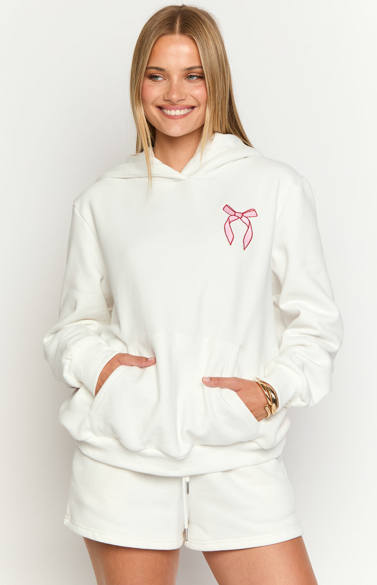 White hoodie with a pink bow embroidery on the left chest and a large front kangaroo pocket