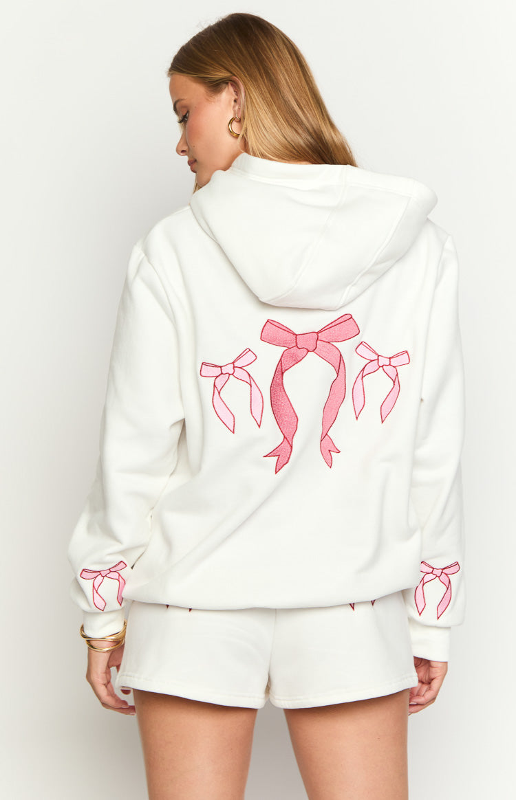 Rear view of a white hoodie with three large pink embroidered bows on the back and small bows on the cuffs