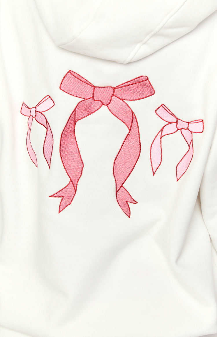 Close-up of the back of a white hoodie with three embroidered pink bows, a large dark pink and two smaller light pink