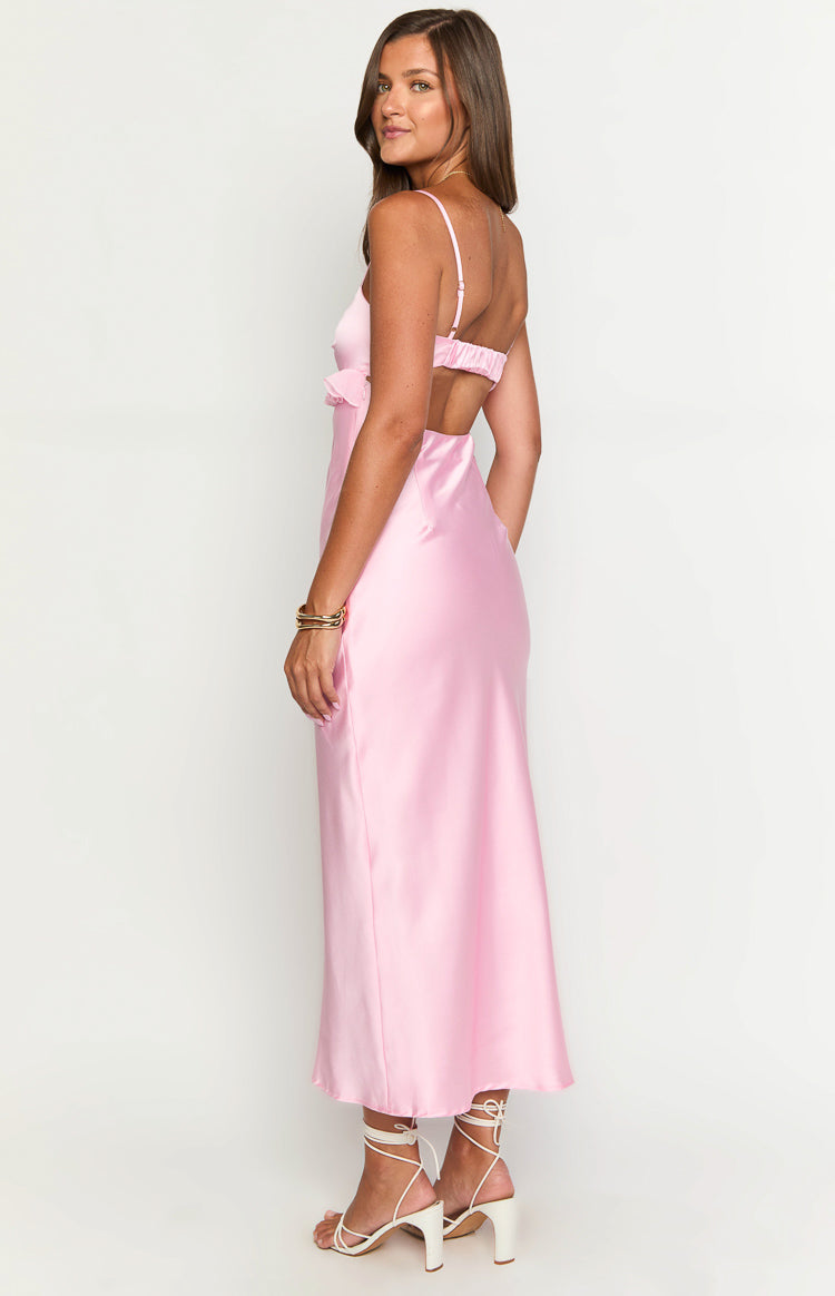 Side view of a pink satin maxi dress with thin straps, an elasticated back band, and a side ruffle detail
