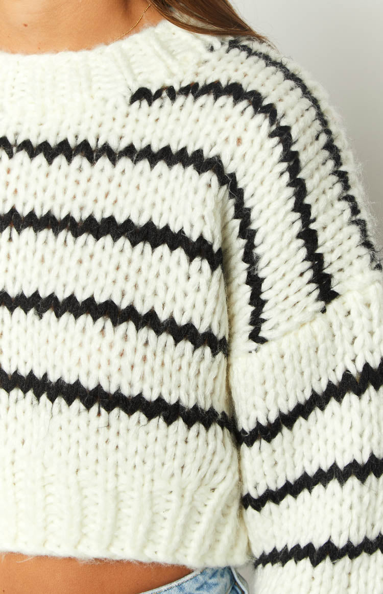 Close-up of the thick white chunky knit sweater with black horizontal stripes across the body and sleeve