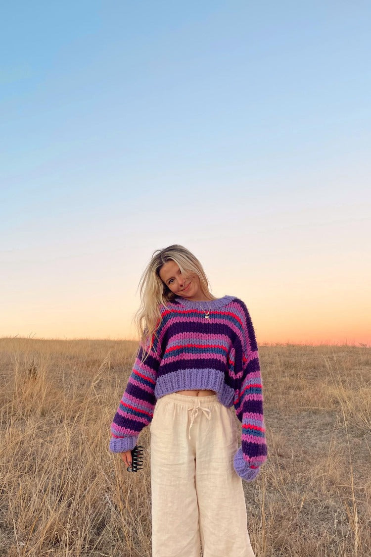 Cropped purple chunky knit sweater with horizontal stripes, a crew neck, and relaxed long sleeves