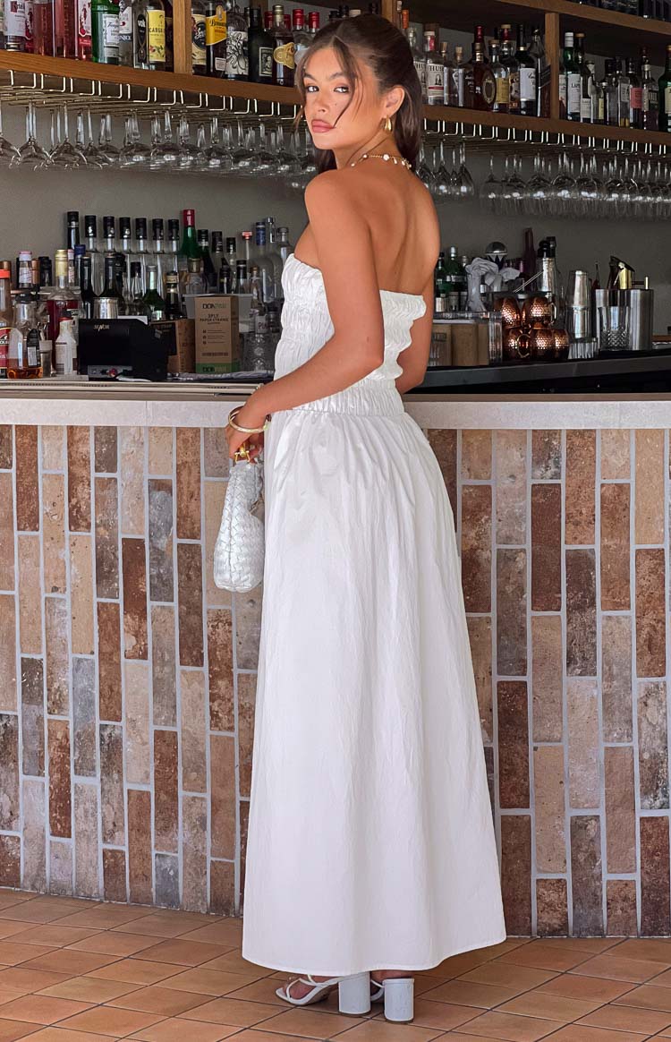 Side-rear view of a white strapless maxi dress with a shirred bust and elasticated waist