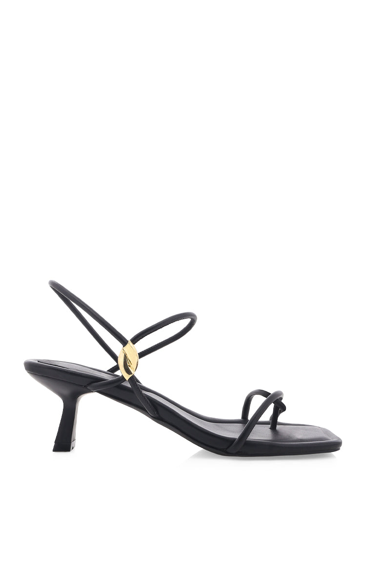 Side view of black heels with thin straps, gold hardware detail, and a square toe