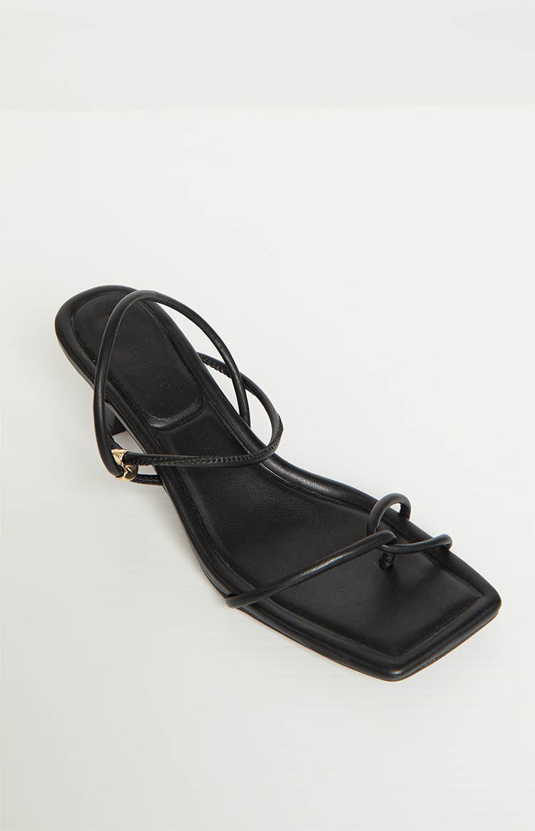 Angled view of a black square toe heel, highlighting the thin straps and looped toe detail