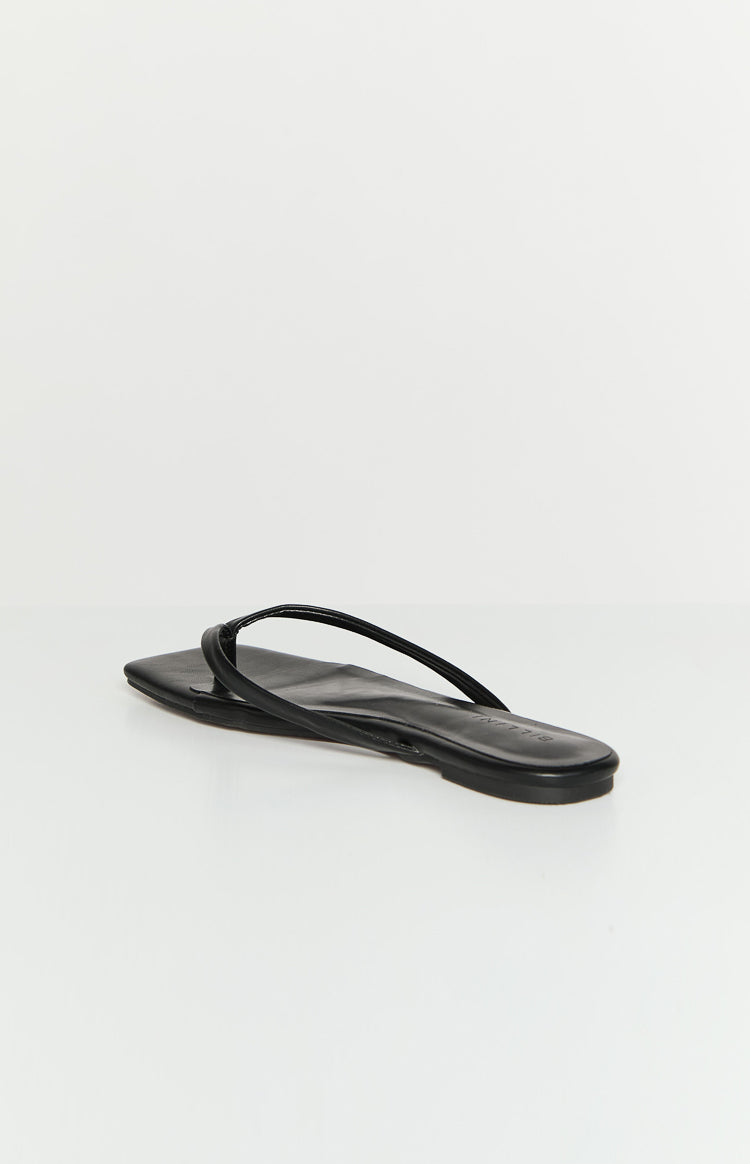 Low angle side view of a black flat with a square toe and thin thong straps