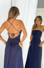 Rear view of a navy satin maxi dress with criss-cross spaghetti straps, a low scoop back, and ruched detail