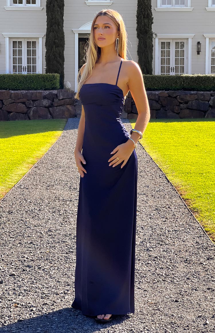 Navy satin maxi dress with a straight neckline, thin spaghetti straps, and subtle side ruching
