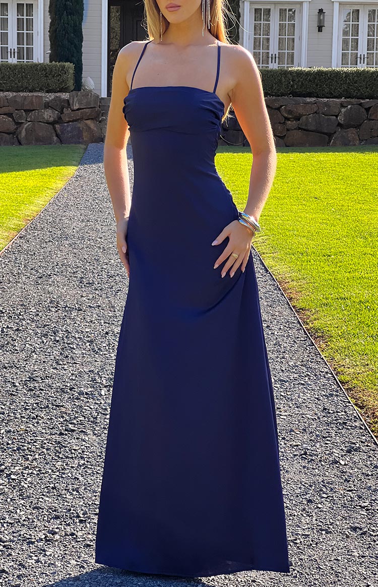 A sleek navy blue satin maxi dress- ideal for a formal or prom event- featuring thin spaghetti straps and a clean- elegant silhouette.