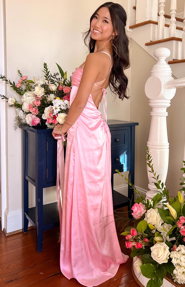 Side view showing the low scoop back with crisscross tie straps and ruched detail on a pink satin maxi dress
