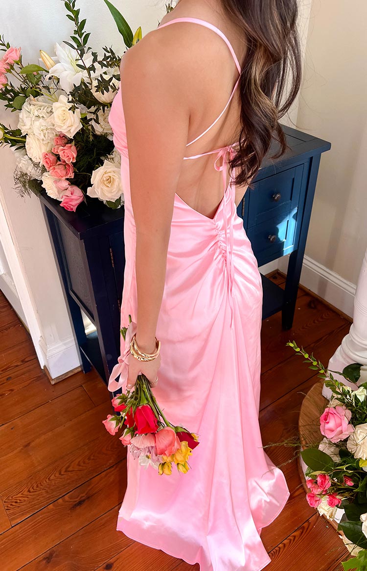 Rear view of a pink satin maxi dress with a low scoop back, criss-cross tie straps, and ruched detail