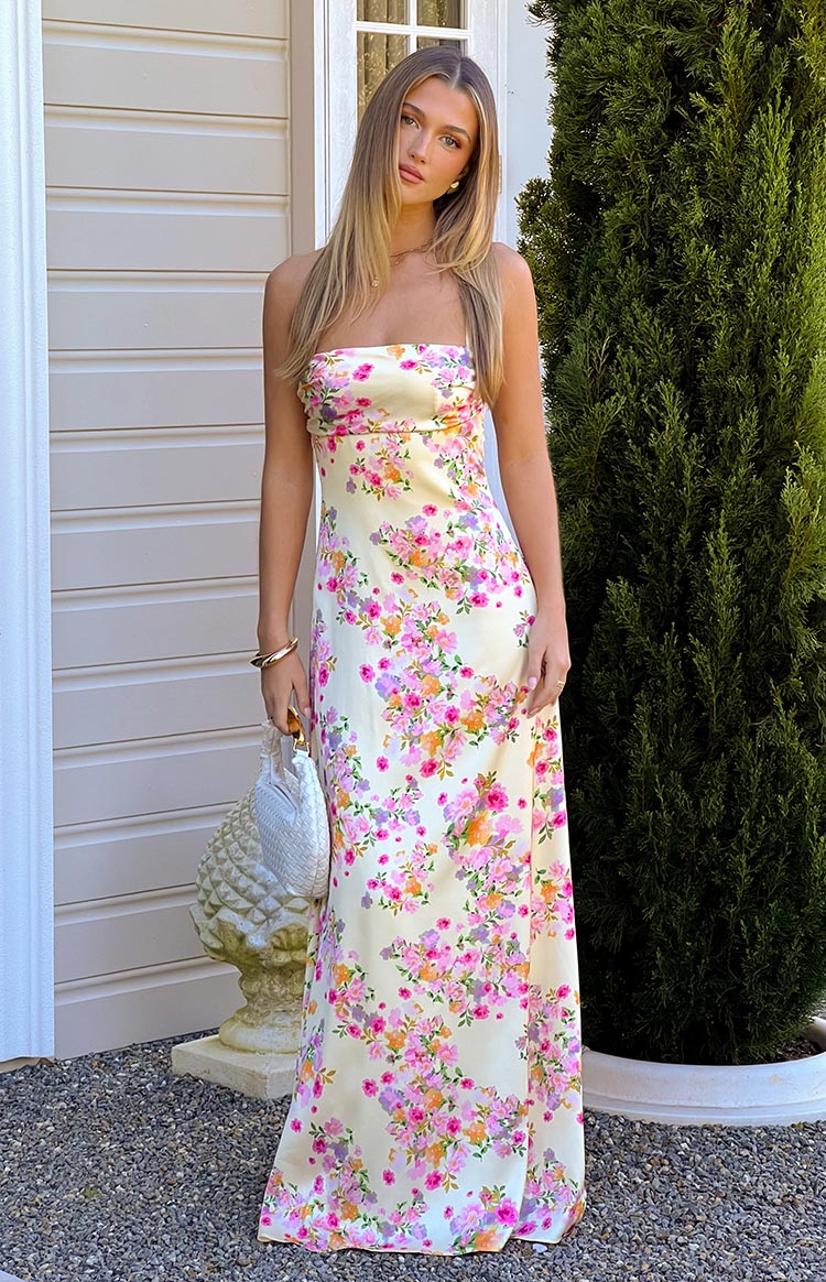 Front view of a yellow satin strapless maxi dress with a vibrant pink and purple floral print