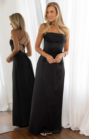 Model in an elegant black satin floor length dress with a square neckline and halter straps. A sophisticated choice for a Formal evening